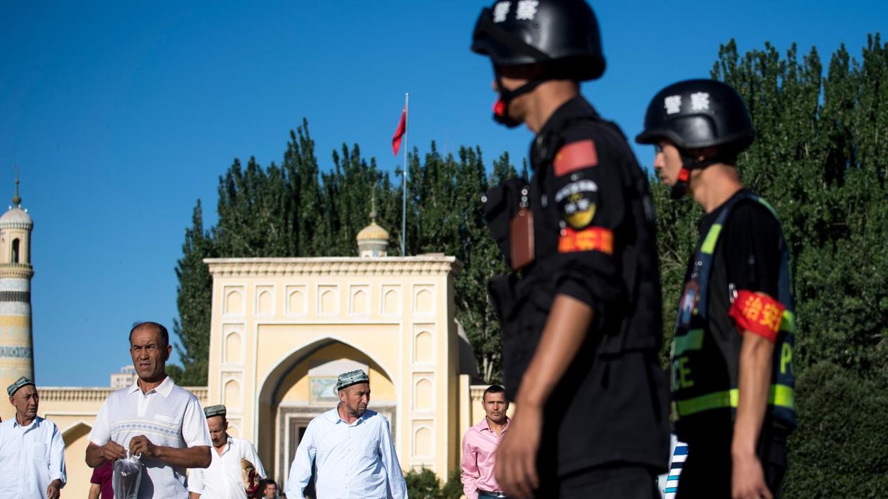 26. Juni 2017 im nordwestchinesischen Kashgar: Polizisten blicken auf Männer, die nach dem Morgengebet die Id-Kah-Moschee verlassen