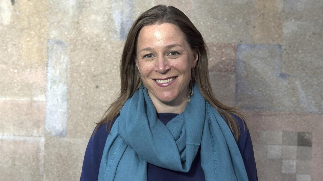 Porträtbild von Annika Reich mit blauem Schaal vor einer Steinwand. Porträtbild von Annika Reich mit blauem Schaal vor einer Steinwand.