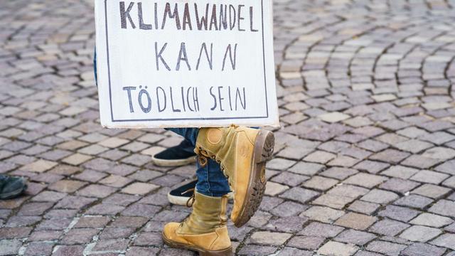 Eine Teilnehmerin des Globalen Fridays for Future Streiks stellt auf ihrem Fuß ein Schild "Klimawandel kann Tödlich sein" ab