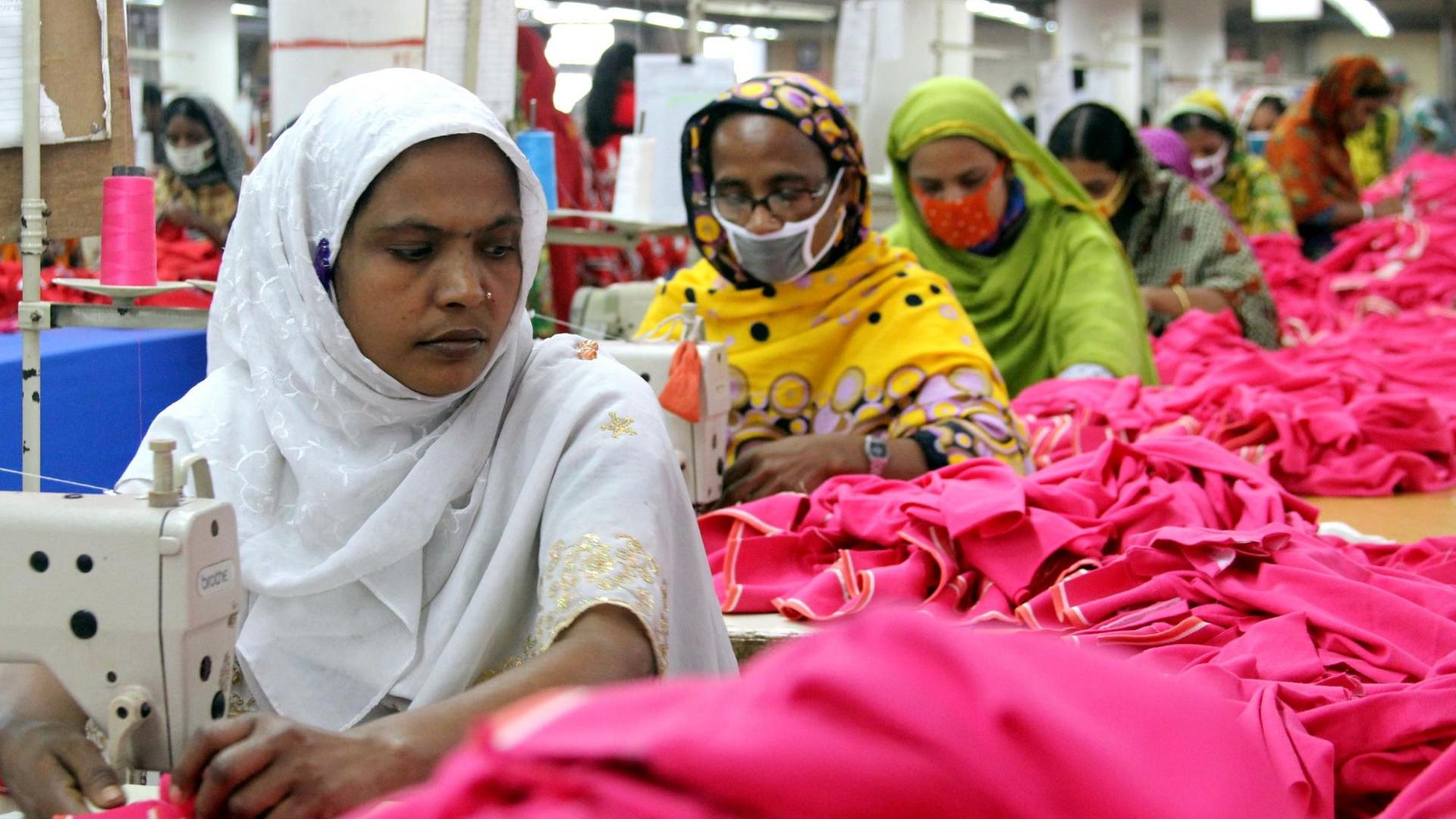 FRauen und Männer arbeiten unter schweren Bedingungen in der Textilfabrik 'One Composite Mills' in Gazipur an Nähmaschinen. FRauen und Männer arbeiten unter schweren Bedingungen in der Textilfabrik 'One Composite Mills' in Gazipur an Nähmaschinen.