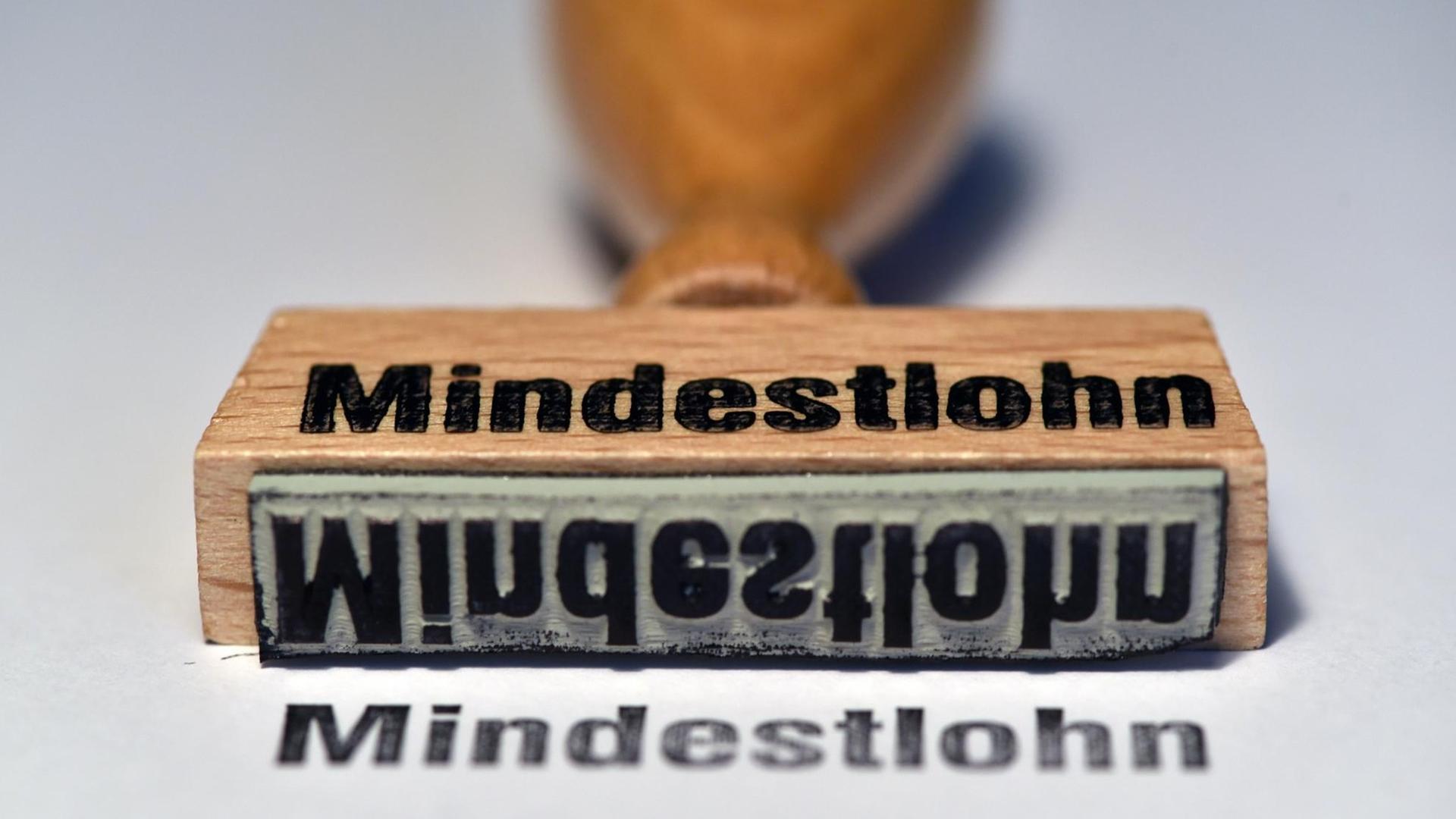 Ein Stempel mit der Aufschrift «Mindestlohn» liegt auf einem Tisch. Ein Stempel mit der Aufschrift «Mindestlohn» liegt auf einem Tisch.