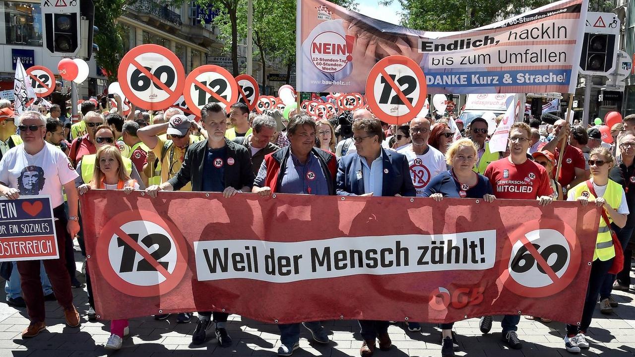 Mehrere Menschen halten an der Spitze eines Demonstrationszuges ein Banner mit der Aufschrift "Weil der Mensch zählt, daneben sind die Zahlen 12 und 60 durchgestrichen. Mehrere Menschen halten an der Spitze eines Demonstrationszuges ein Banner mit der Aufschrift "Weil der Mensch zählt, daneben sind die Zahlen 12 und 60 durchgestrichen.