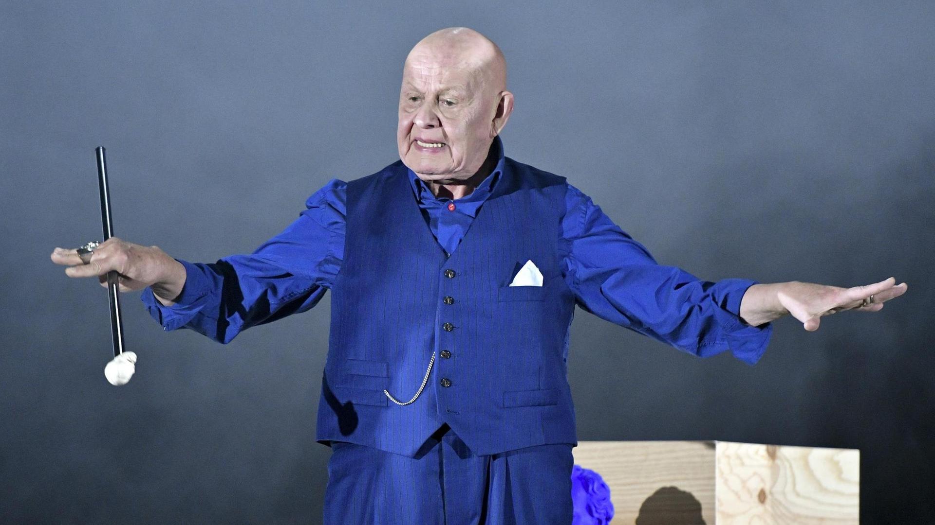 Das Bild zeigt den Schauspieler Ignaz Kirchner in einem blauen Anzug auf der Bühne.