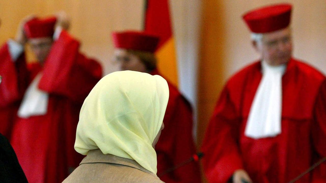 Fereshta Ludin, muslimische Lehrerin und Beschwerdeführerin im Kopftuch-Streit, sitzt am 24.9.2003 nach der Urteilsverkündung im Bundesverfassungsgericht in Karlsruhe vor den Richtern (l-r) Rudolf Mellinghoff, Lerke Osterloh und Hans-Joachim Jentsch. Die Bundesländer dürfen muslimischen Lehrerinnen das Kopftuchtragen im Unterricht verbieten. Dazu müssen sie jedoch nach dem Urteil des Bundesverfassungsgerichts eine "hinreichend bestimmte" gesetzliche Grundlage schaffen. Diese fehlt derzeit in Baden-Württemberg. Das Land habe deshalb mit seiner Ablehnung, Ludin in den Schuldienst zu übernehmen, ihre Religionsfreiheit verletzt, entschieden die Richter. Fereshta Ludin, muslimische Lehrerin und Beschwerdeführerin im Kopftuch-Streit, sitzt am 24.9.2003 nach der Urteilsverkündung im Bundesverfassungsgericht in Karlsruhe vor den Richtern (l-r) Rudolf Mellinghoff, Lerke Osterloh und Hans-Joachim Jentsch. Die Bundesländer dürfen muslimischen Lehrerinnen das Kopftuchtragen im Unterricht verbieten. Dazu müssen sie jedoch nach dem Urteil des Bundesverfassungsgerichts eine "hinreichend bestimmte" gesetzliche Grundlage schaffen. Diese fehlt derzeit in Baden-Württemberg. Das Land habe deshalb mit seiner Ablehnung, Ludin in den Schuldienst zu übernehmen, ihre Religionsfreiheit verletzt, entschieden die Richter.