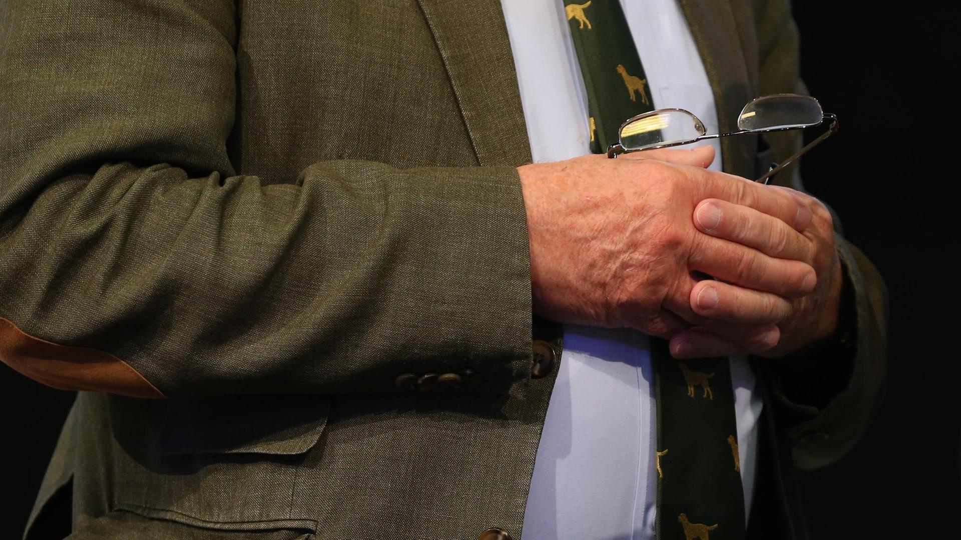 Alexander Gauland steht auf einem Podium und hält seine Brille. Auf dem Bild sind seine Hände sowie sei Bauch zu sehen. Alexander Gauland steht auf einem Podium und hält seine Brille. Auf dem Bild sind seine Hände sowie sei Bauch zu sehen.