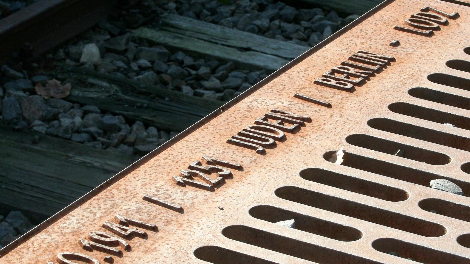Eine beschriftete Metallplatte des Mahnmals Gleis 17 liegt auf dem früheren Verladebahnsteig des Güterbahnhofs Grunewald in Berlin. Eine beschriftete Metallplatte des Mahnmals Gleis 17 liegt auf dem früheren Verladebahnsteig des Güterbahnhofs Grunewald in Berlin.