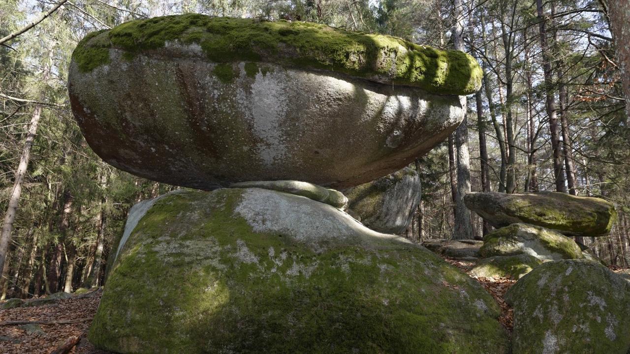 Zwei große Granitsteine liegen ausbalanciert aufeinander im Wald. Zwei große Granitsteine liegen ausbalanciert aufeinander im Wald.