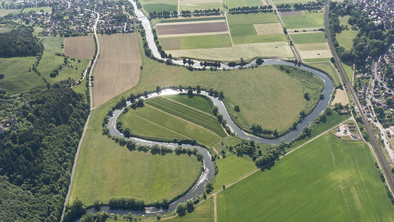 Luftaufnahme eines sich durch eine Wiesenlandschaft schlängelnden Flusses Luftaufnahme eines sich durch eine Wiesenlandschaft schlängelnden Flusses