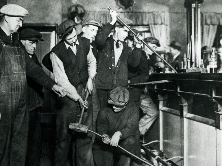 Eine Gruppe Männer reißt mit Brechstangen die Bar in einer amerikanischen Bar ab.