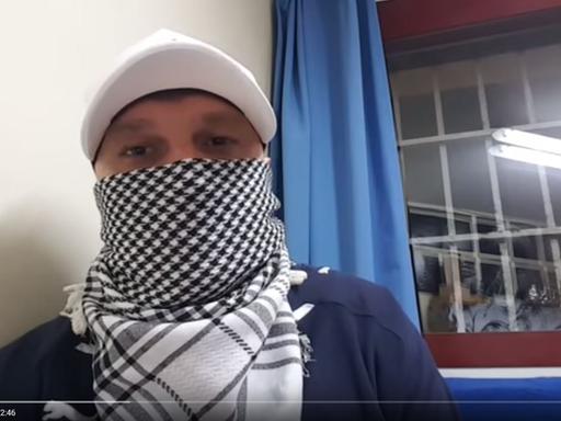 Vlogger mit Basecap und Palästinensertuch vor dem Gesicht in einem Video des Youtube-Kanals "Knast Vlog".