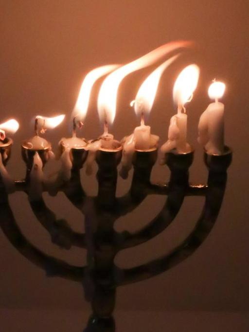 Flackernde Kerzenflammen in einer Menorah.
