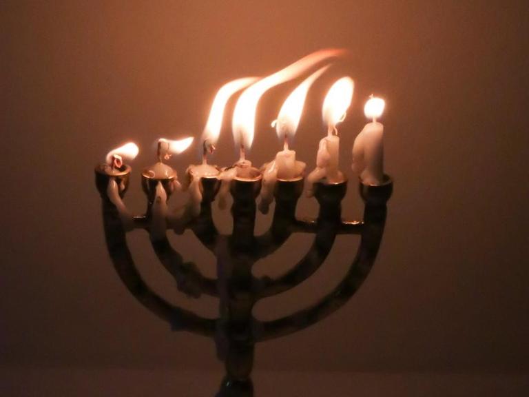 Flackernde Kerzenflammen in einer Menorah.