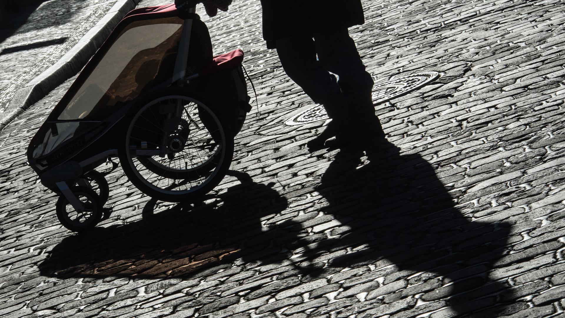 Schatten einer Mutter mit ihrem Kinderwagen auf dem Kopfsteinpflaster Schatten einer Mutter mit ihrem Kinderwagen auf dem Kopfsteinpflaster