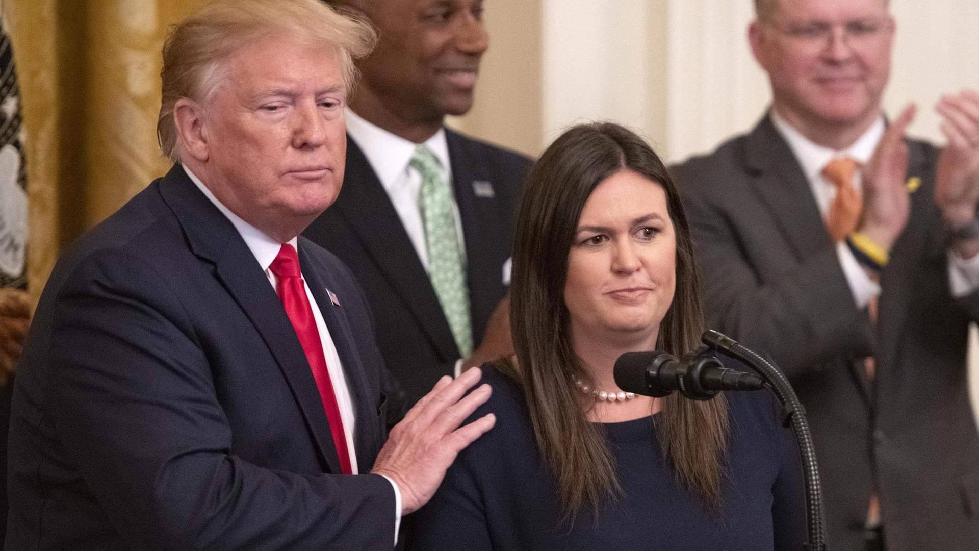 Trump mit Sanders, der er die Hand auf die Schulter legt am Tag ihres Rücktritts im Weißen Haus Trump mit Sanders, der er die Hand auf die Schulter legt am Tag ihres Rücktritts im Weißen Haus