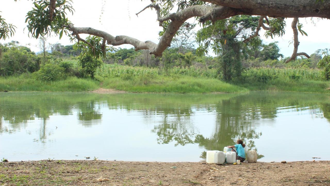 Eine Frau füllt Wasser in Kanister am Stausee Matuya in Maria La Baja Eine Frau füllt Wasser in Kanister am Stausee Matuya in Maria La Baja