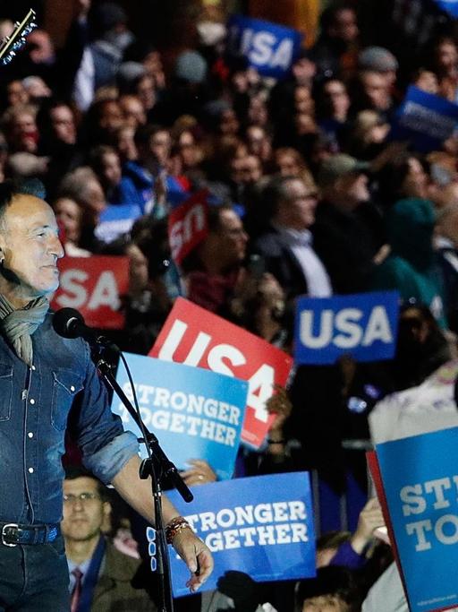 Bruce Springsteen tritt vor den Wählern von Hillary Clinton auf und hält seine Gitarre zur Begrüßung in die Höhe. (2016)