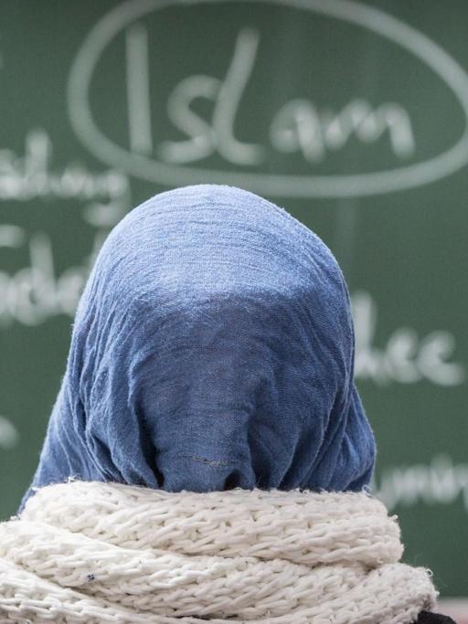 Eine Schülerin mit Kopftuch sitzt bei einer Unterrichtsstunde zum Thema Islam
