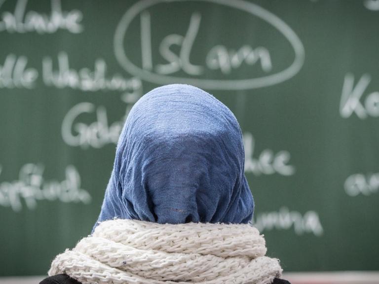 Eine Schülerin mit Kopftuch sitzt bei einer Unterrichtsstunde zum Thema Islam