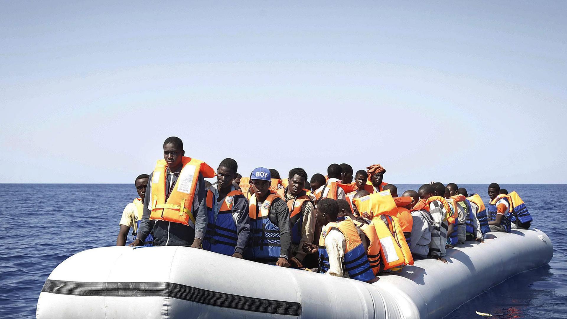 Flüchtlinge aus Afrika stehen in einem Schlauchboot, das im Mittelmeer treibt - sie werden schließlich von einem italienischen Rettungsschiff geborgen. Flüchtlinge aus Afrika stehen in einem Schlauchboot, das im Mittelmeer treibt - sie werden schließlich von einem italienischen Rettungsschiff geborgen.