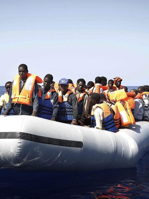 Flüchtlinge aus Afrika stehen in einem Schlauchboot, das im Mittelmeer treibt - sie werden schließlich von einem italienischen Rettungsschiff geborgen.