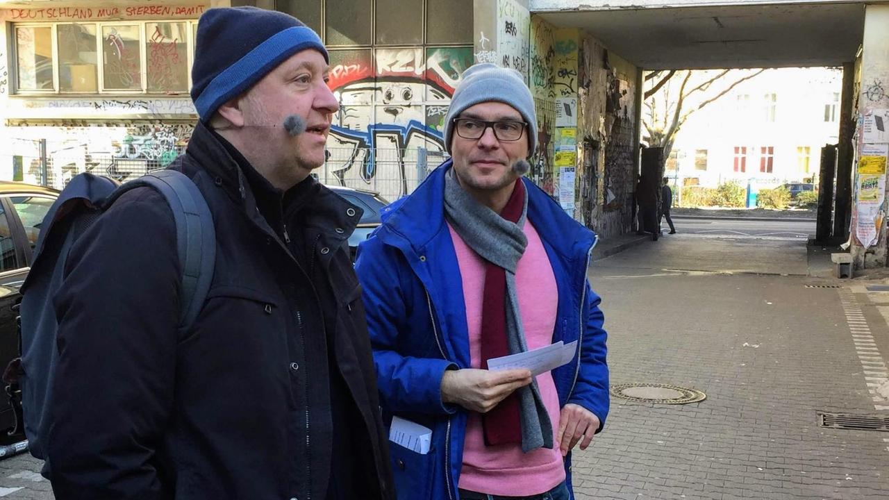 Der Kabarettist Horst Evers mit Moderator Korbinian Frenzel in einem Kreuzberger Hinterhof. Zu sehen ist die Hinterhofkulisse vom Mehringhof-Theater.