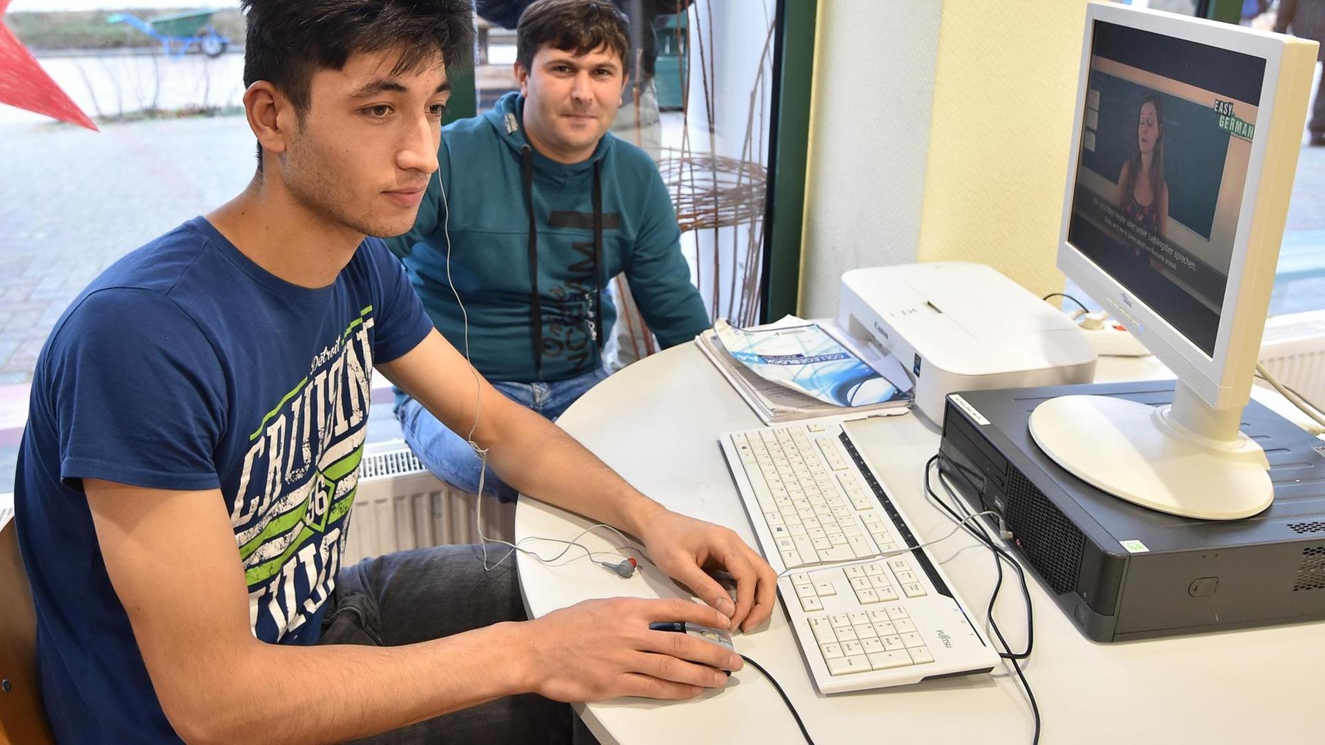 Zwei Männer an einem Computer in einer Erstaufnahmeeinrichtung für Asylsuchende