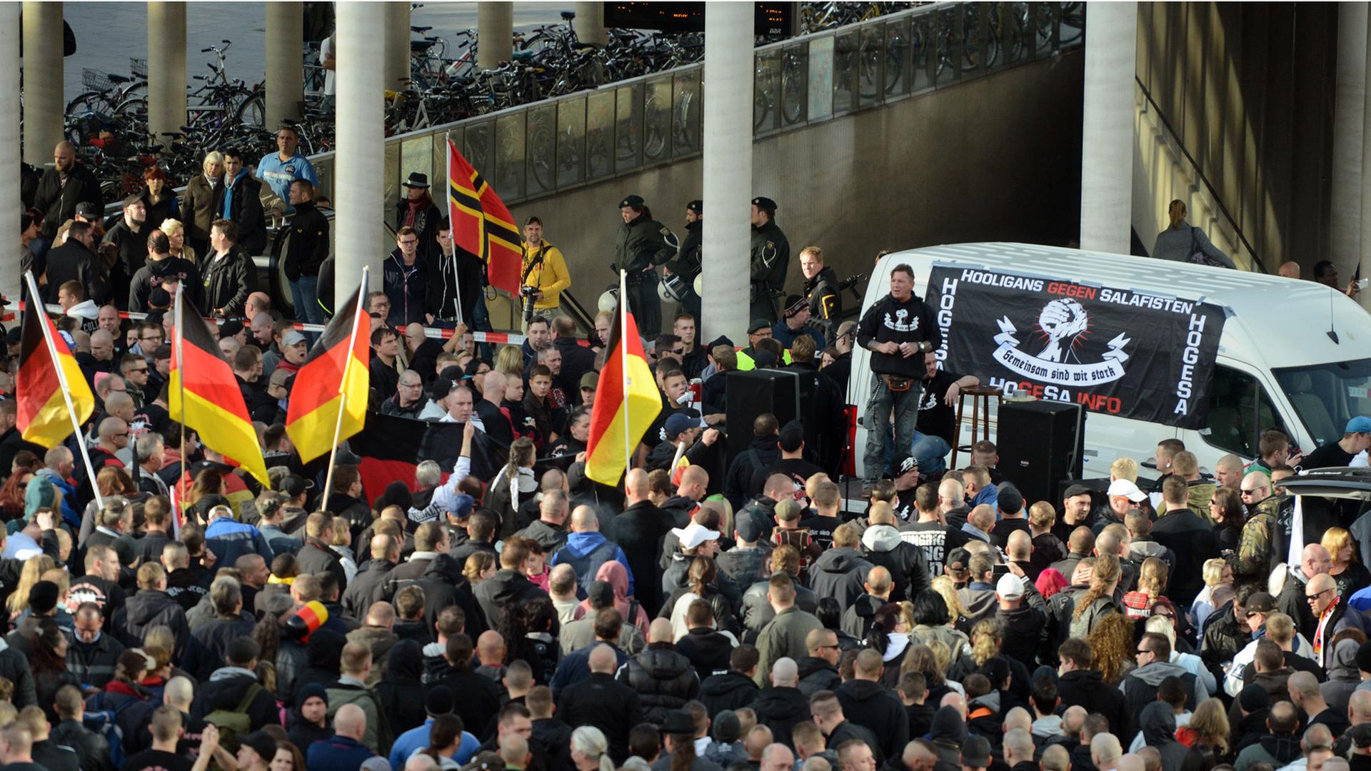 Demonstranten stehen am 26.10.2014 in Köln vor einem Fahrzeug mit einem Transparent der als gewaltbereit bekannten Gruppe "Hooligans gegen Salafisten".