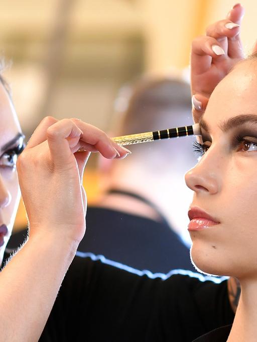 Eine Visagistin schminkt ein Model bei der Berliner Fashion Week 2016.