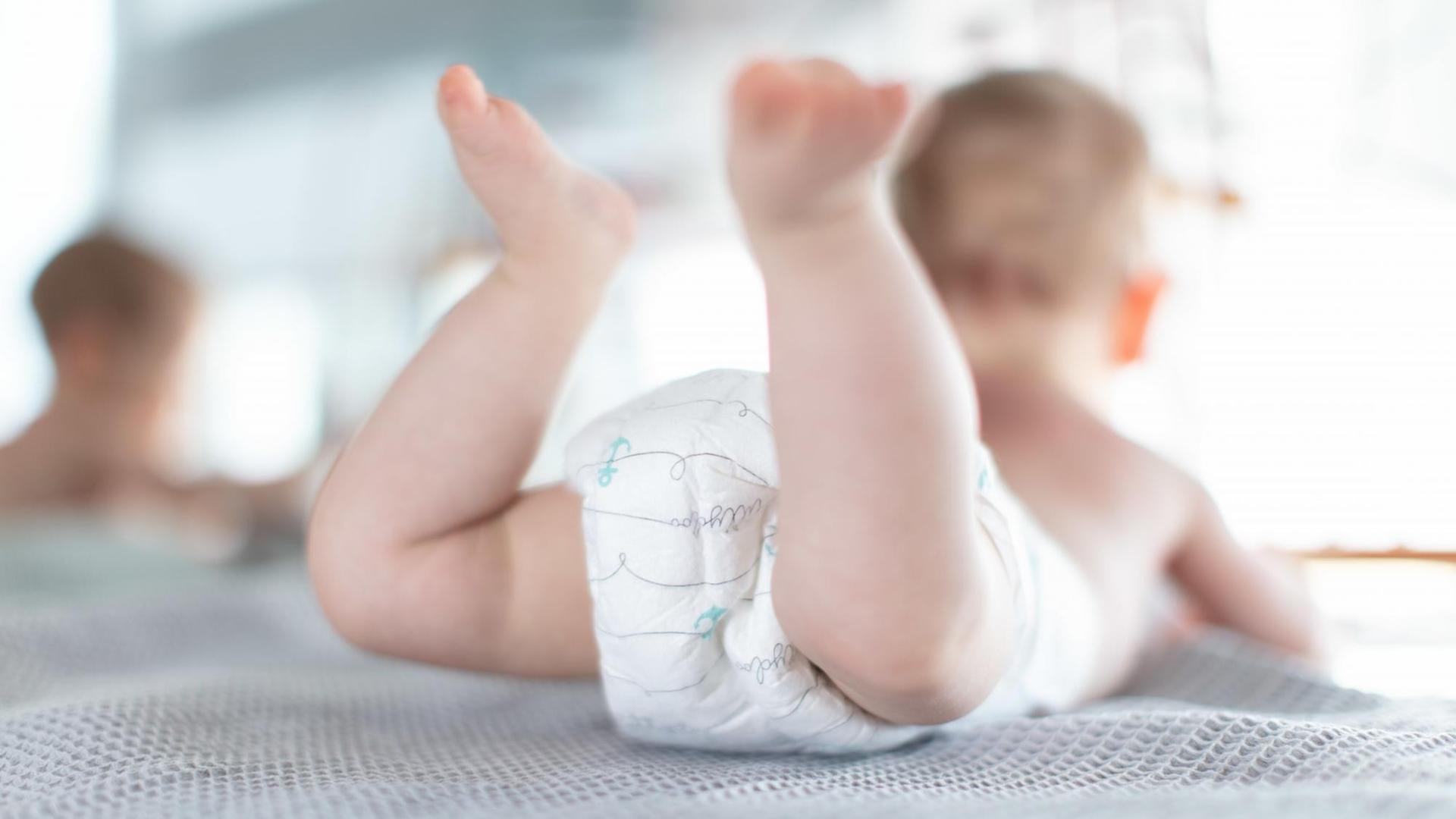 Ein Säugling trägt Pampers, während er auf einer Kommode liegt. Ein Säugling trägt Pampers, während er auf einer Kommode liegt.