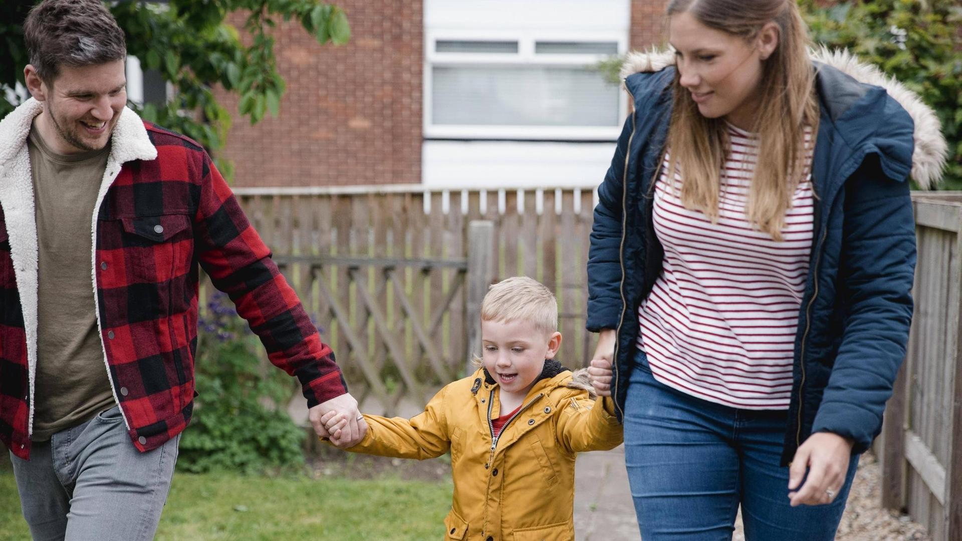 Vater und Mutter mit ihrem kleinen Sohn an der Hand Vater und Mutter mit ihrem kleinen Sohn an der Hand