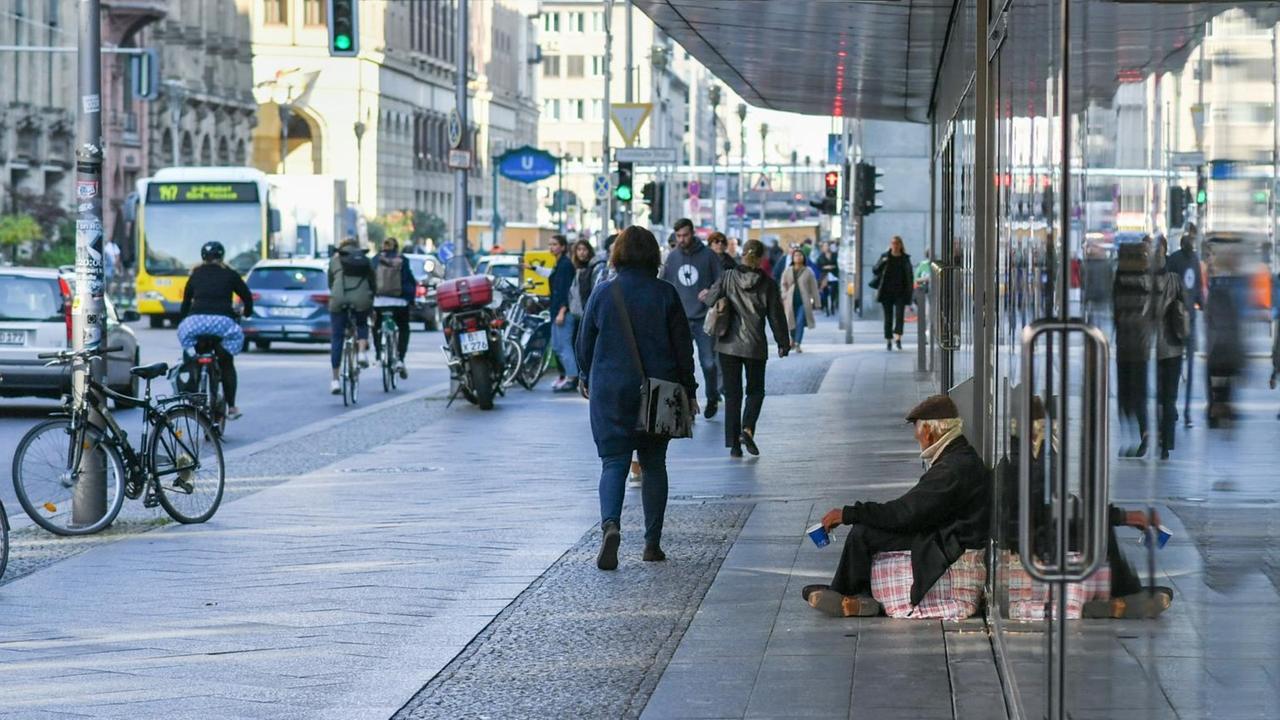 Ein Mann sitzt auf dem Gehweg und bettelt Ein Mann sitzt auf dem Gehweg und bettelt