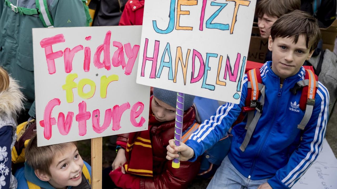 Drei junge Schulkinder zwischen sieben und acht Jahren demonstrieren am 22. März 2019 in Berlin im Rahmen der Proteste "Friday for Future". Sie halten ein Schild mit der Aufschrift "Jetzt handeln" nach oben. Drei junge Schulkinder zwischen sieben und acht Jahren demonstrieren am 22. März 2019 in Berlin im Rahmen der Proteste "Friday for Future". Sie halten ein Schild mit der Aufschrift "Jetzt handeln" nach oben.