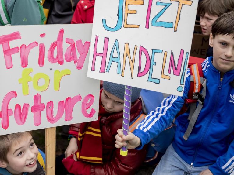 Drei junge Schulkinder zwischen sieben und acht Jahren demonstrieren am 22. März 2019 in Berlin im Rahmen der Proteste "Friday for Future". Sie halten ein Schild mit der Aufschrift "Jetzt handeln" nach oben.