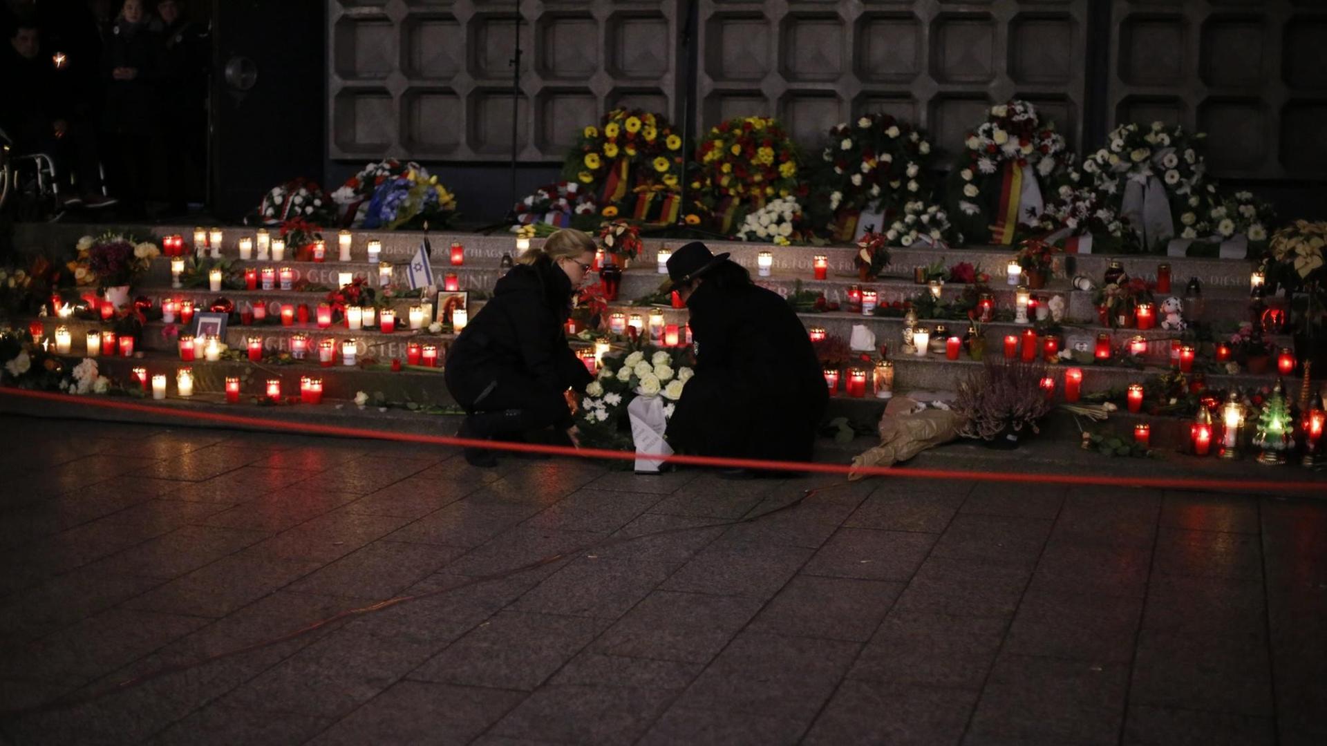 Menschen hocken an einer mit Kerzen bestellten Treppe am Breitscheidplatz