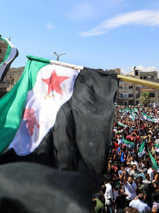 In Idlib dmeonstrieren am 7. September 2018 tausende Menschen gegen eine mögliche Militäroffensive der Regierungstruppen. Sie schwenken Flaggen von Oppositionsgruppen.