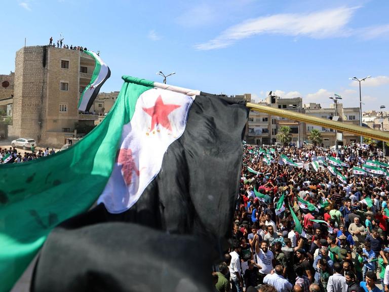 In Idlib dmeonstrieren am 7. September 2018 tausende Menschen gegen eine mögliche Militäroffensive der Regierungstruppen. Sie schwenken Flaggen von Oppositionsgruppen.