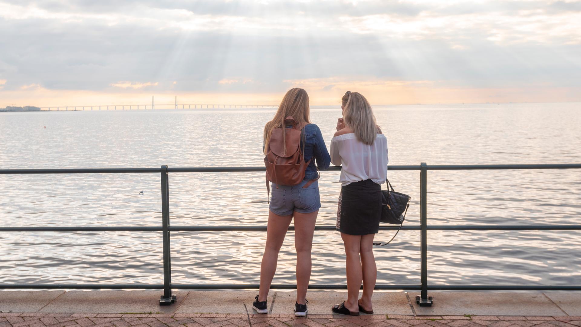 Zwei junge Frauen von hinten an einem Seeufer. Zwei junge Frauen von hinten an einem Seeufer.