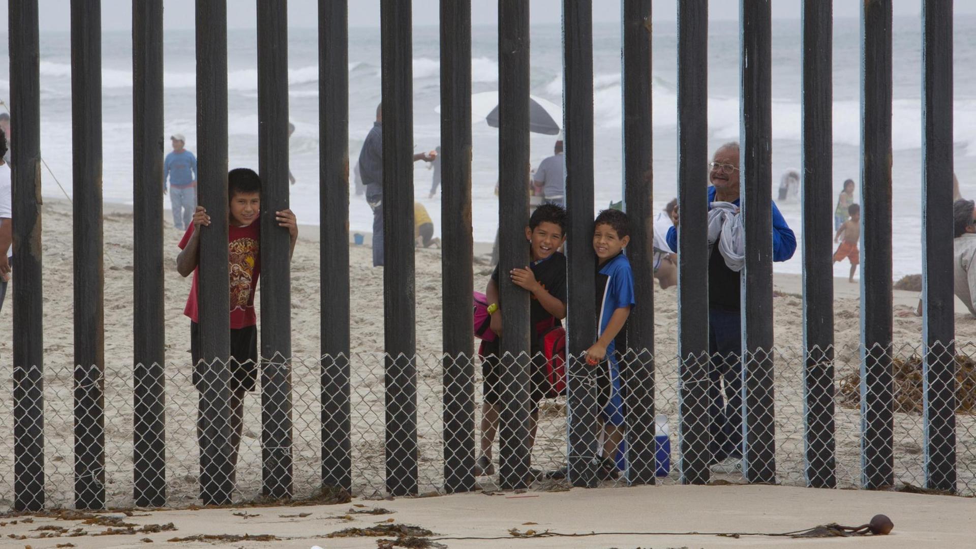 Kinder schauen durch einen Zaun von Mexiko in die USA. Kinder schauen durch einen Zaun von Mexiko in die USA.
