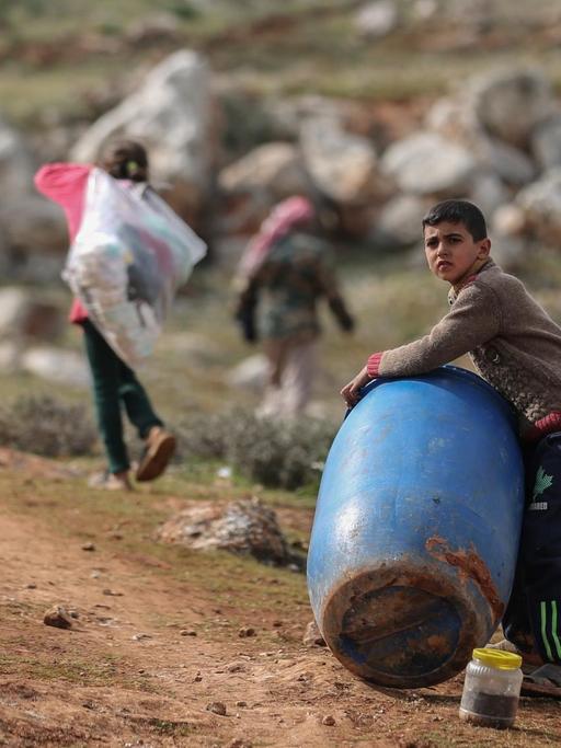 Ein syrischer Junge hält ein Plastikfass in der Nähe eines behelfsmäßigen Lagers für Familien, die infolge der Bombardierung und der Militäroperationen aus dem Idlib-Land vertrieben wurden.