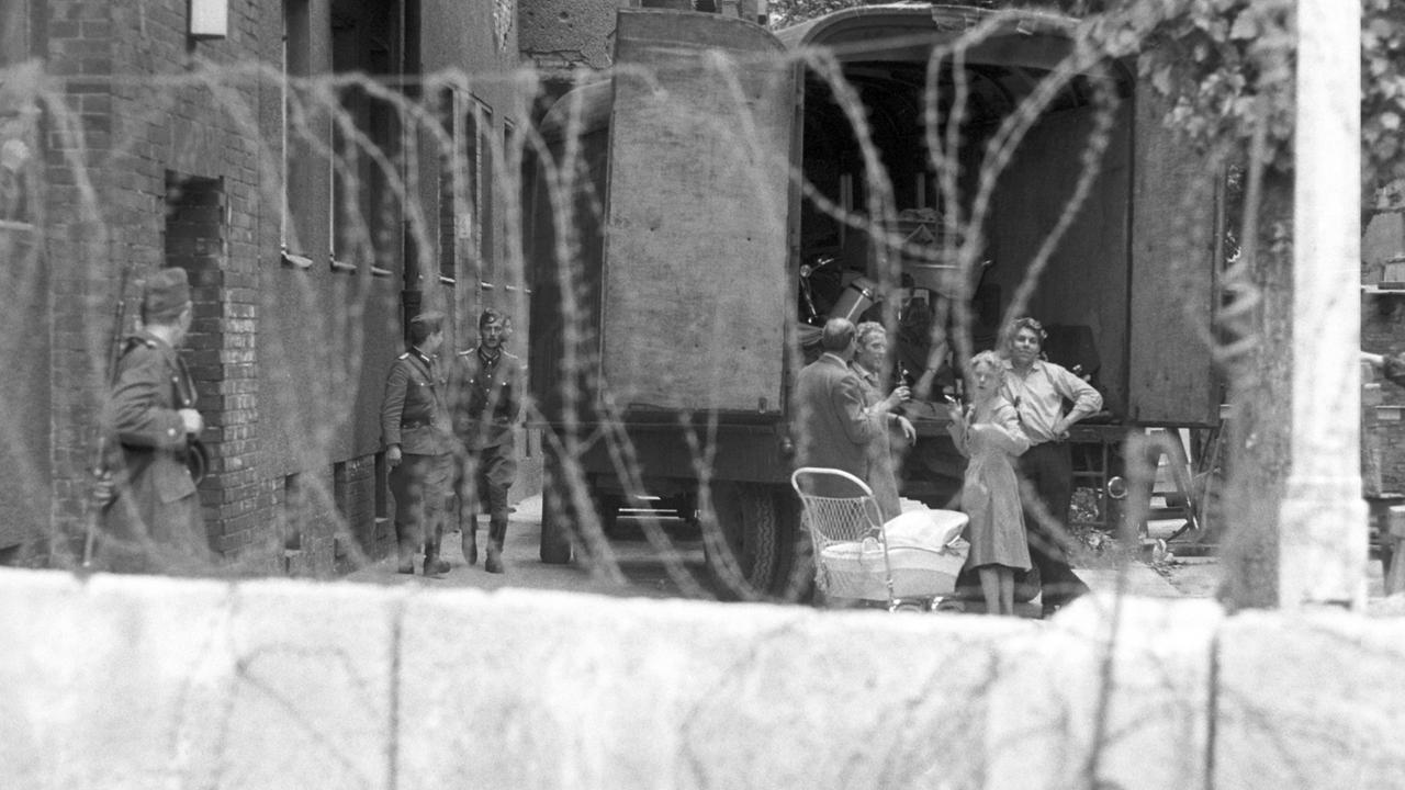 Eine Familie hinter Stacheldraht, bewacht von Volkspolizisten der DDR während der Zwangsräumung von Häusern in der Bernauer Straße in Berlin, 1961. Direkt an der Bernauer Straße verlief die Grenze zwischen West- und Ostberlin. Eine Familie hinter Stacheldraht, bewacht von Volkspolizisten der DDR während der Zwangsräumung von Häusern in der Bernauer Straße in Berlin, 1961. Direkt an der Bernauer Straße verlief die Grenze zwischen West- und Ostberlin.