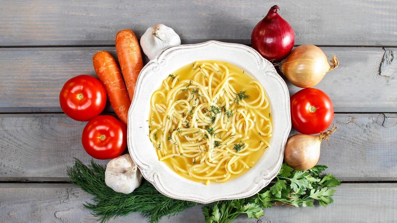 Obst und Gemüse liegen um einen Teller Nudelsuppe. Obst und Gemüse liegen um einen Teller Nudelsuppe.