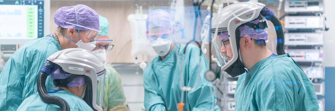 Auf einer Intensivstation stehen Ärzte und Pfleger in mit Schutzmasken am Bett eines Covid-Intensivpatienten. Auf einer Intensivstation stehen Ärzte und Pfleger in mit Schutzmasken am Bett eines Covid-Intensivpatienten.