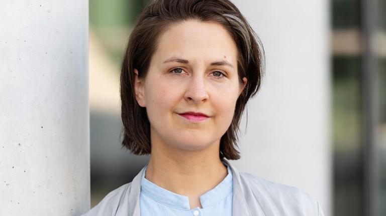 Die Rechtsphilosophin Dana Schmalz lehnt an einem Betonpfeiler und schaut freundlich in die Kamera. Die Rechtsphilosophin Dana Schmalz lehnt an einem Betonpfeiler und schaut freundlich in die Kamera.