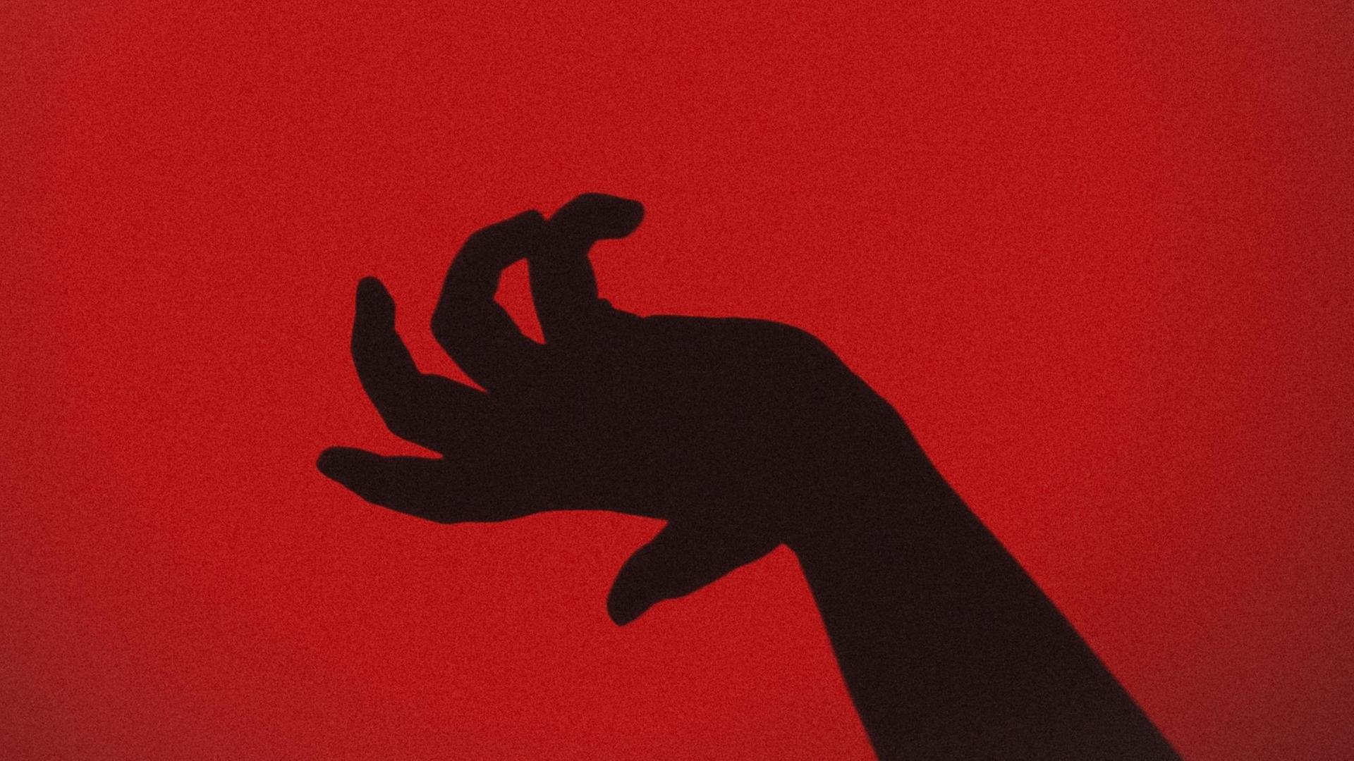 Die Silhouette einer Hand vor einem roten Hintergrund Die Silhouette einer Hand vor einem roten Hintergrund