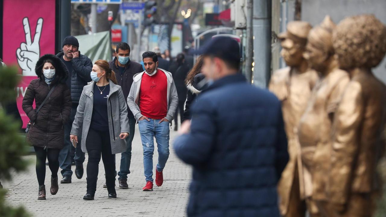 Personen auf einem Gehweg in der Stadt — einige tragen Masken, andere nicht. Personen auf einem Gehweg in der Stadt — einige tragen Masken, andere nicht.