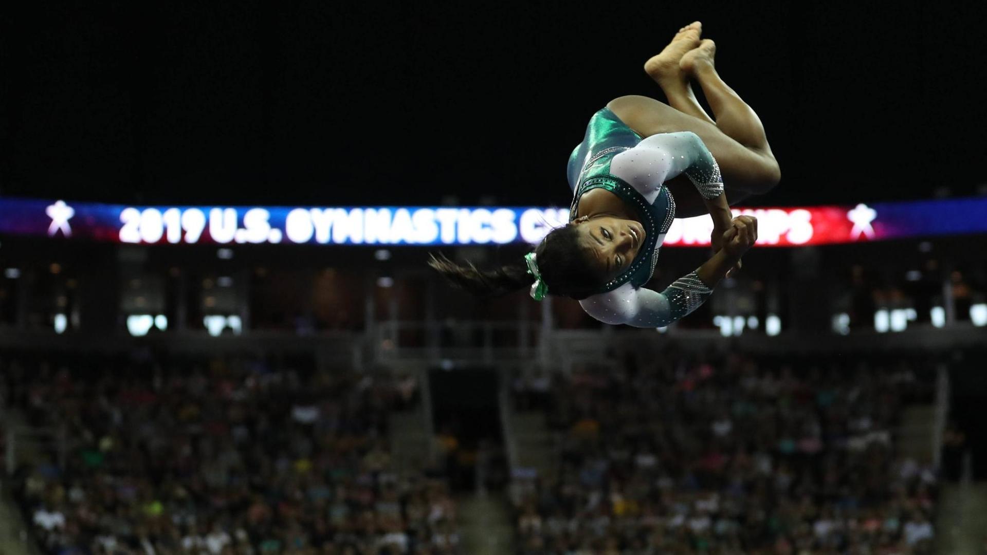 Simone Biles turnt einen Schraubensalto Simone Biles turnt einen Schraubensalto
