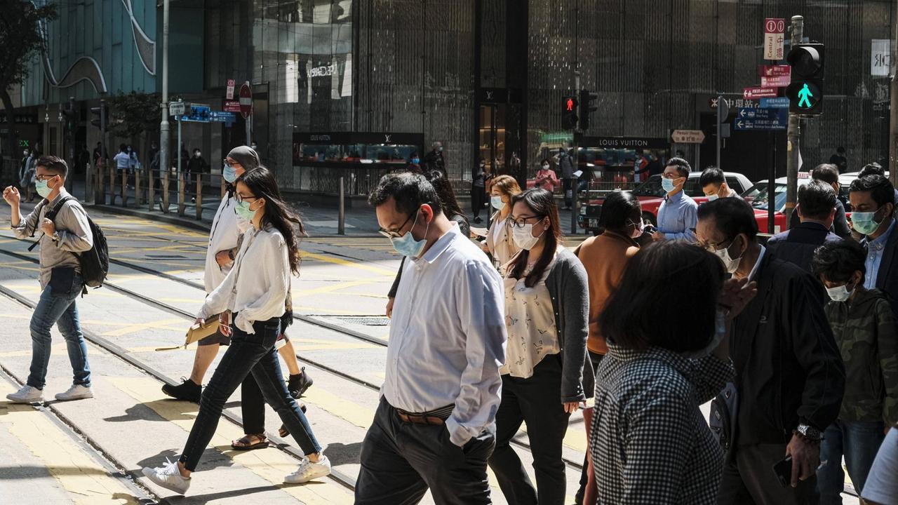 Menschen mit Schutzmasken in Hong Kong überqueren einen Zebrastreifen. Menschen mit Schutzmasken in Hong Kong überqueren einen Zebrastreifen.