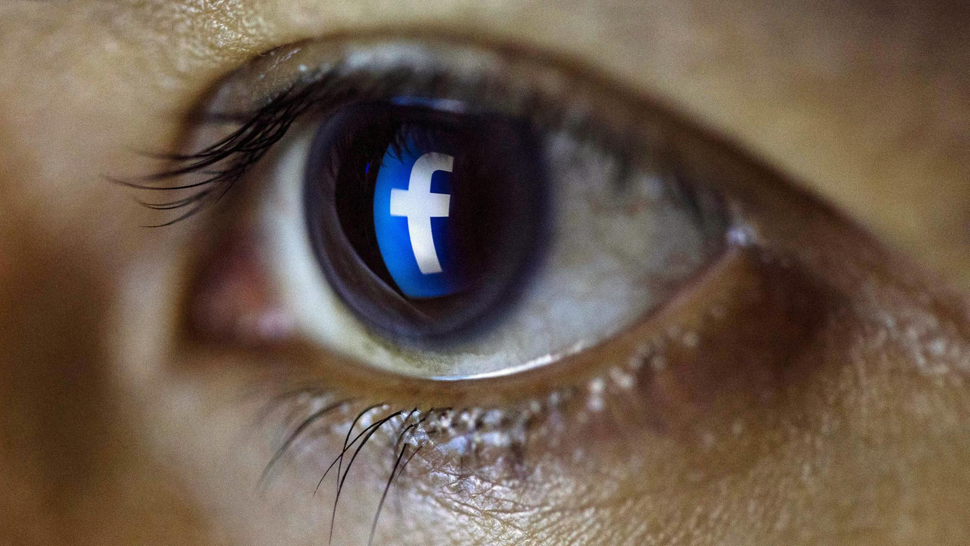 Ein Tablet-Benutzer blickt auf ein Facebook-Logo. Ein Tablet-Benutzer blickt auf ein Facebook-Logo.
