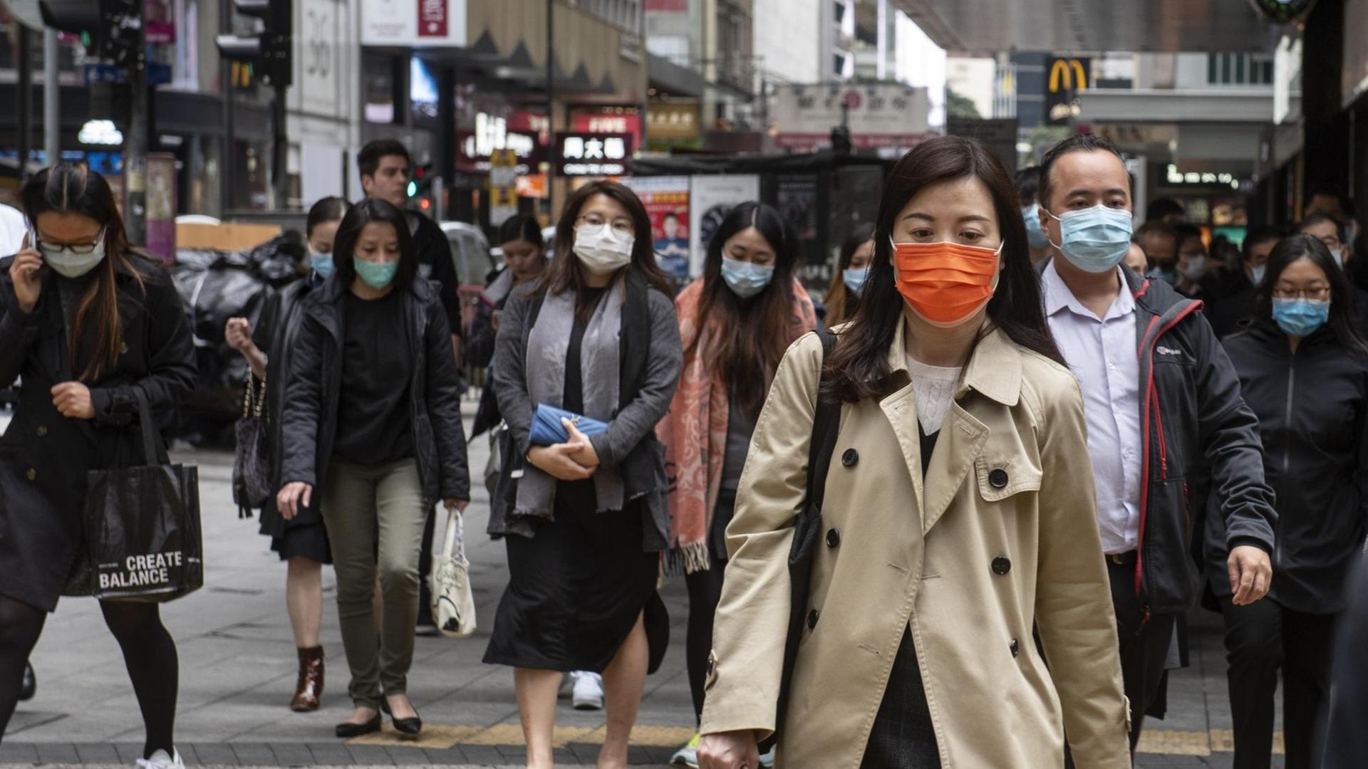 Menschen mit Mund-Nasen-Schutz auf einer Geschäftsmeile in Hongkong Menschen mit Mund-Nasen-Schutz auf einer Geschäftsmeile in Hongkong