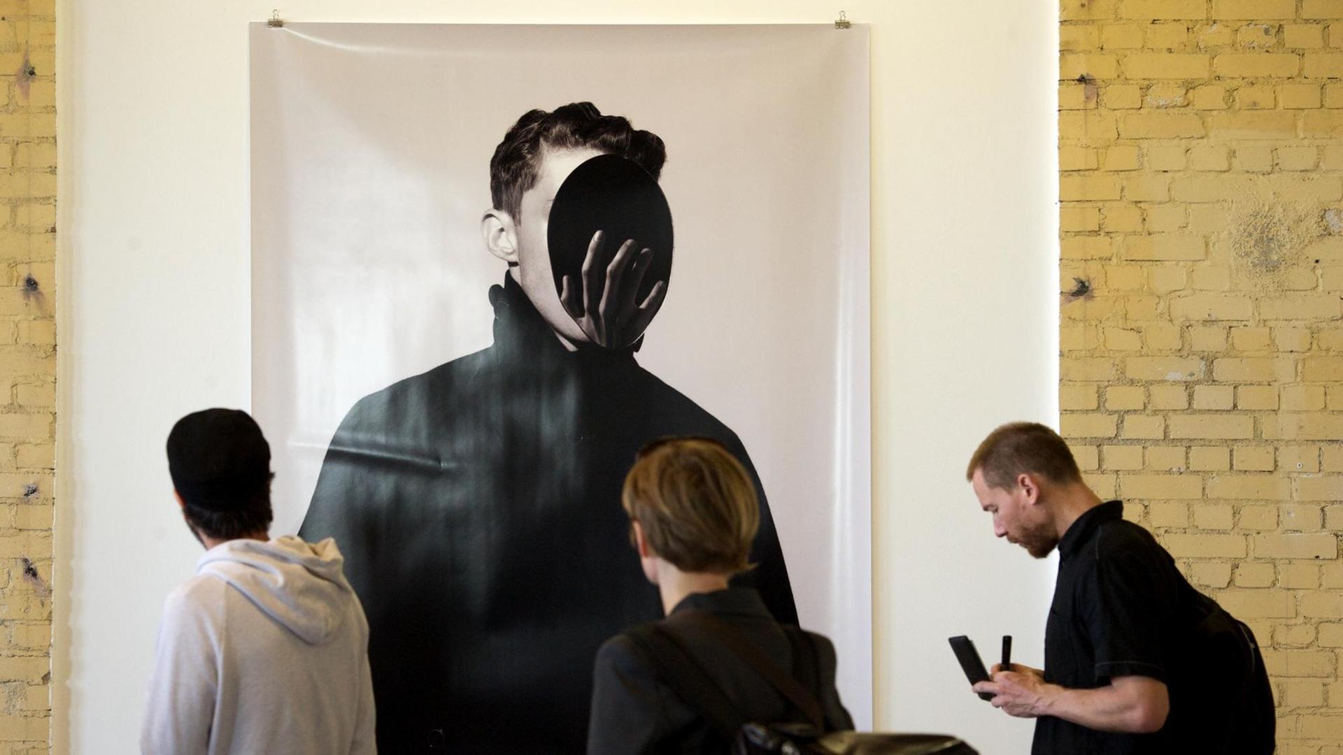 Besucher schauen sich die Fotografie "o.T." von Daniel Sannwald auf dem internationalen Fotografie-Festival in Leipzig im Jahr 2014 an.
